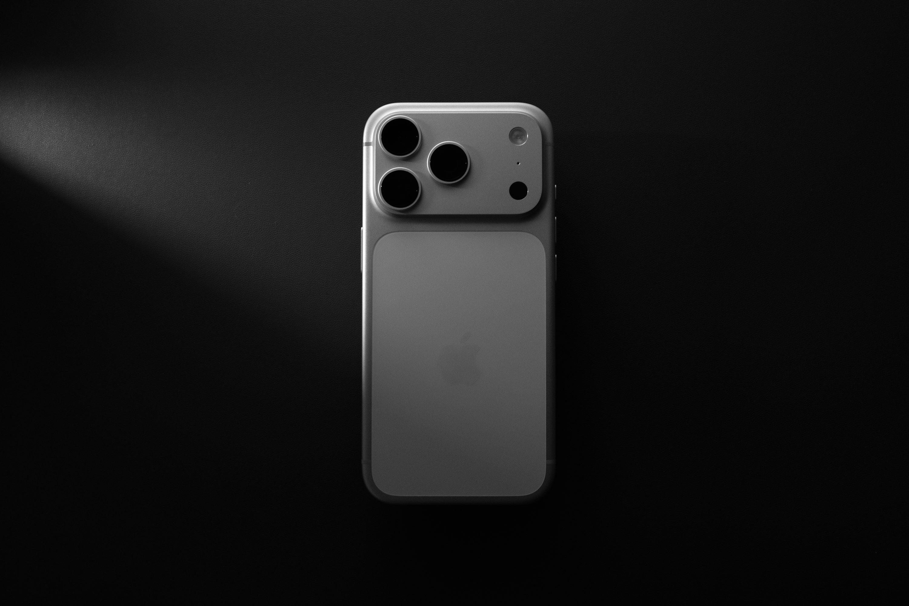 夜のような暗い背景に置かれたシルバーのスマートフォン